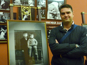 Петр Любимов у стенда с детскими фото отца