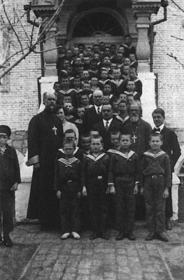Директор «Русского дома» К.И. Подольский с настоятелем домовой Иоанно-Богословской церкви прот.  С. Литвинцевым (справа), прот.  И. Черёмухиным и воспитанниками приюта. 1931. Источник: Коростелёв В.В., Караулов А.К. Православие в Маньчжурии: 1898–1956: оч