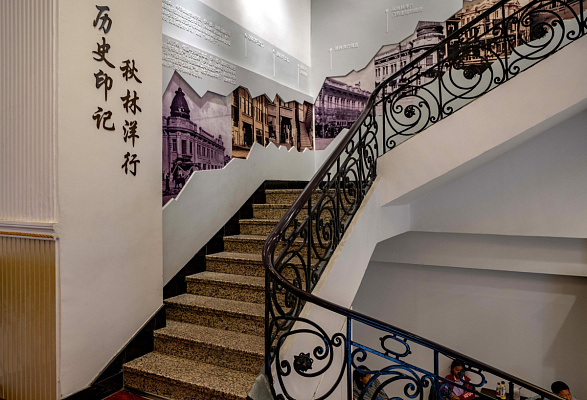 Интерьер  торгового дома «Цулинь». Винтовая лестница с таймлайн истории компании «И.Я. Чурин и Ко» и харбинских магазинов Чурина. Сентябрь 2024. Фото Елизаветы Кириной
